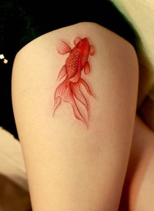 Pretty golden fish tattoo on thigh